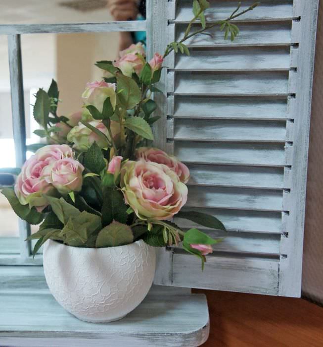 Ένα δοχείο με ανθισμένα τριαντάφυλλα σε ένα ξύλινο περβάζι