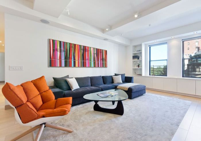 Design av en hvit stue med en oransje lenestol i interiøret