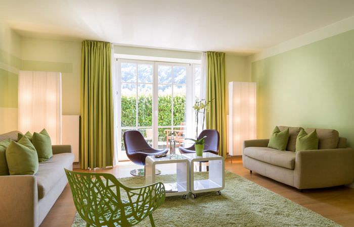 Měkké zelené stěny v obývacím pokoji se dvěma pohovkami