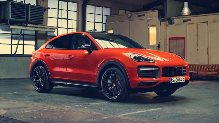 foran porsche cayenne coupe i orange med sorte aluminiumsfælge i stor hal