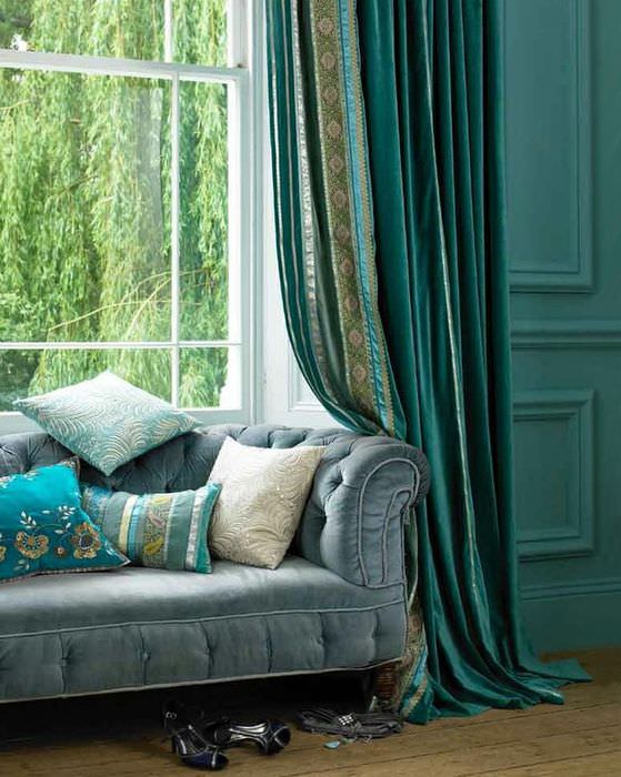 Kanapé a nappali ablaka előtt smaragd függönyökkel