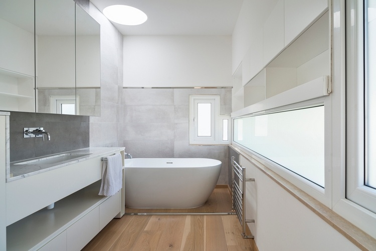 minimalistisk designet badeværelse med spejlbadekar, håndvask og entrégulv