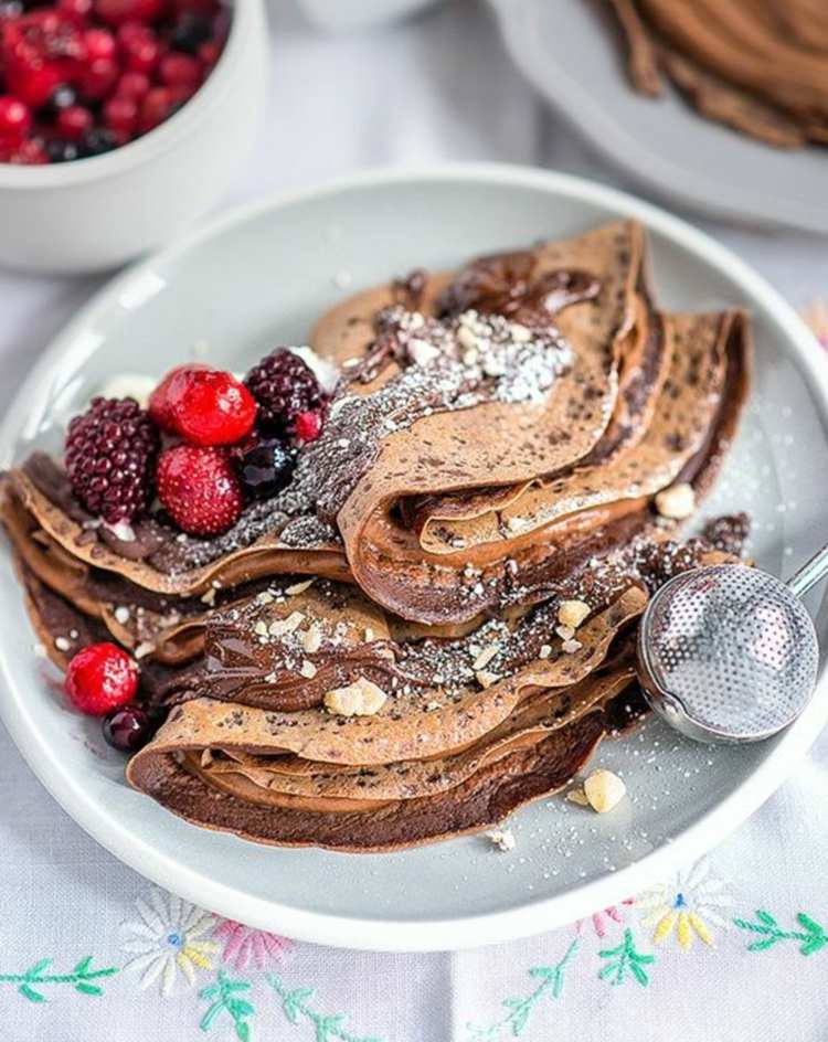 pandekage-mel-chokolade-skovfrugter-pulveriseret sukker-nødder-tallerken-kakao-dug-mønster