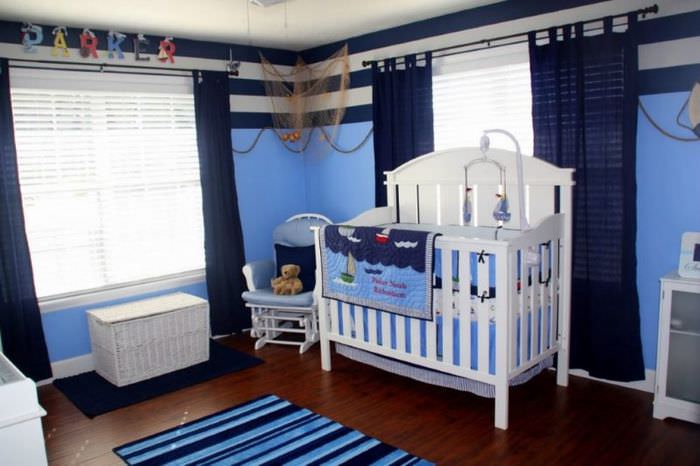 سرير أطفال أبيض لطفل في غرفة بها ستائر زرقاء