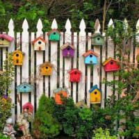 Vidéki kerítés díszítése dekoratív madárházakkal