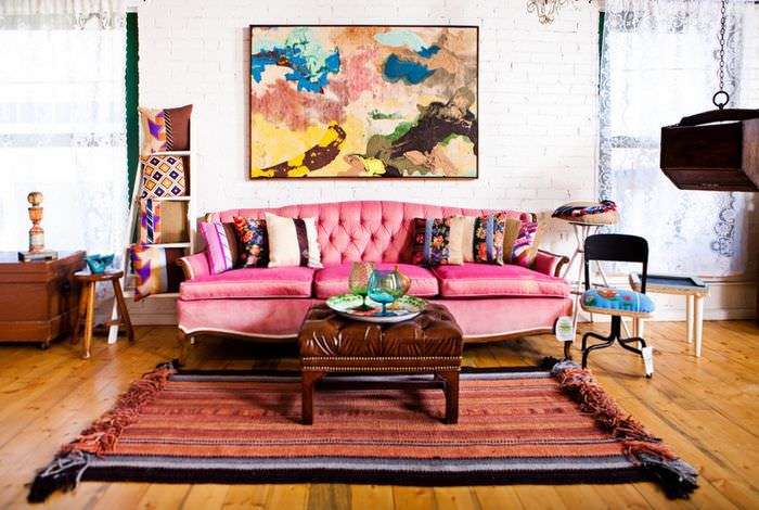 Vaaleanpunainen sohva boho-tyylisessä maalaistalossa