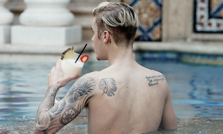 justin bieber tatoveringer bag øret overarm og ryg med cocktail i hånden