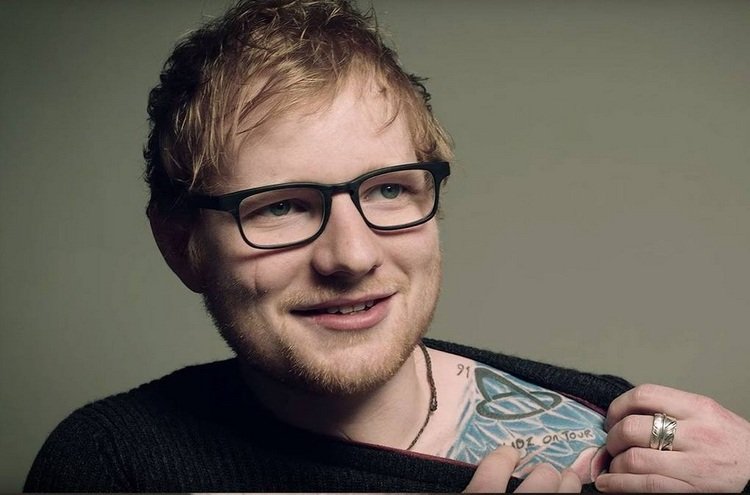 foto af ed sheeran, der peger på sin tatovering på skulderen