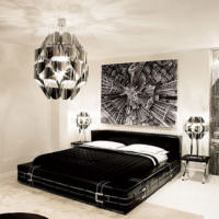 Schwarzes Bett mit weißen Kissen in einem hellgrauen Zimmer