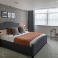 Schlafzimmer in Grautönen und orangefarbener Tagesdecke auf dem Bett