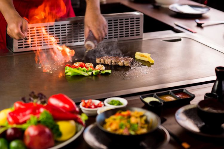 teppanyaki fad griller japansk madlavning eksotiske retter fisk og skaldyr forbereder ild slukker paprika grøntsager svinekød vestlig smag