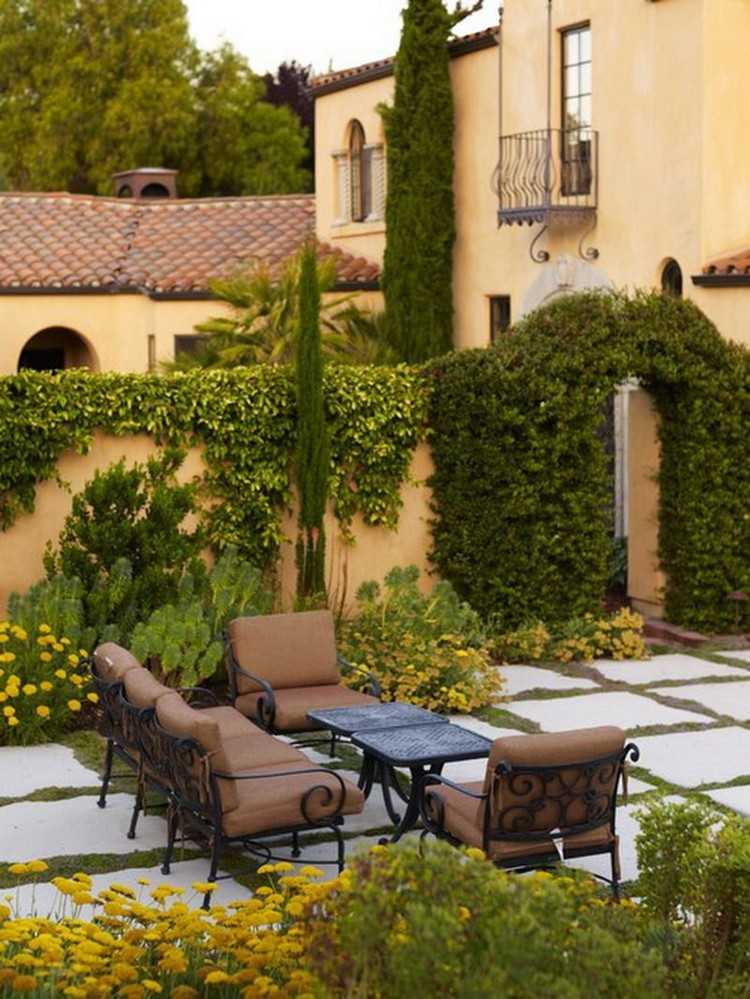 Toscansk terrasse med smedejernsmøbler og frodig vegetation