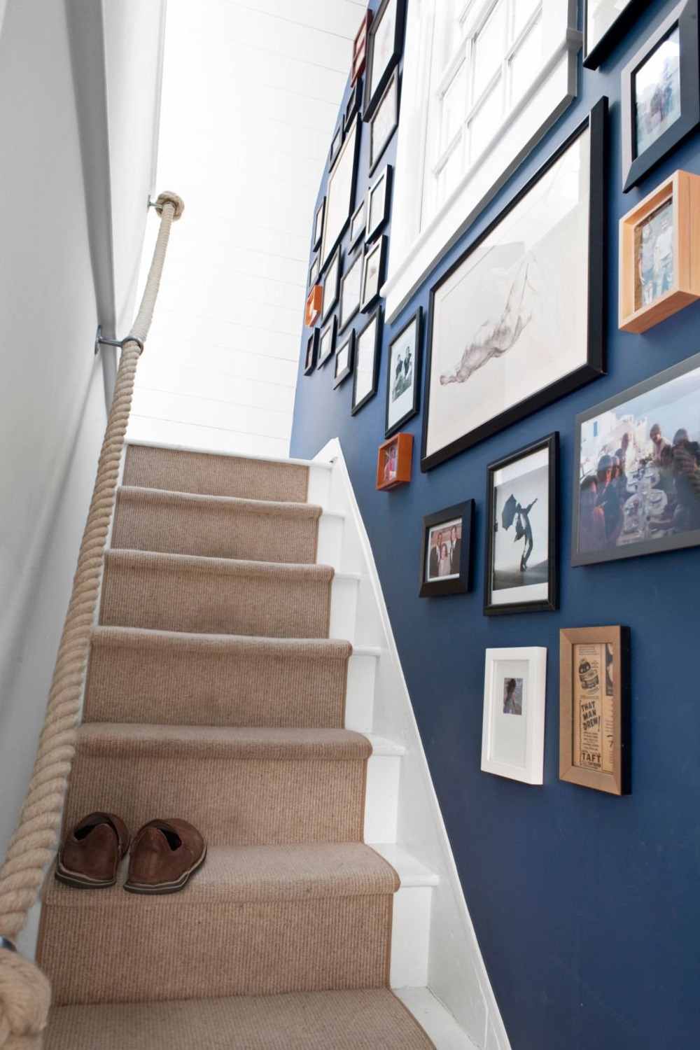 lysebrunt tæppeløber på trapper med trappevæg i blå dekoreret med fotos