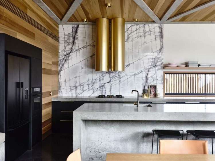 Køkkenøen i betonlook kombineret med sorte skabe og natursten