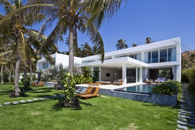 minimalistisk hus med palmetræer og liggestole