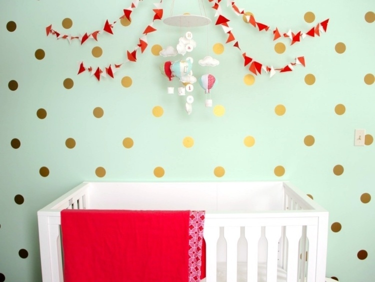væg-farve-mynte-grøn-baby-værelse-baby-seng-væg-dekoration-prikker-mobil-rød-tæppe-hvid-guld