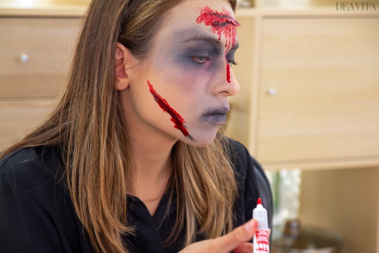 Zombie-make-up påfører falsk blod på kinden